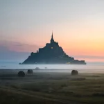 Lever de soleil avec brume sur le Mont-Saint-Michel photographié en pose longue.
