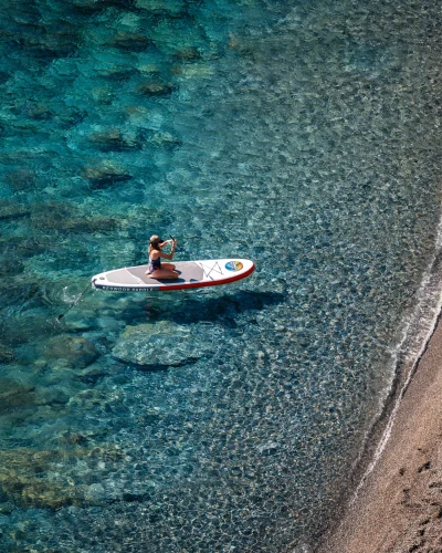 Personne pratiquant le paddle sur une eau cristalline.